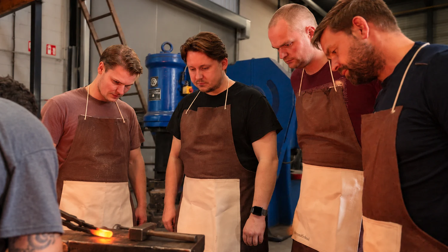 Deelnemers rond het aambeeld tijdens een workshop bij Smeedlokaal